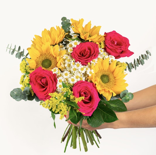 Colorful bouquet featuring vibrant sunflowers, pink roses, and greenery, perfect for celebrations.
