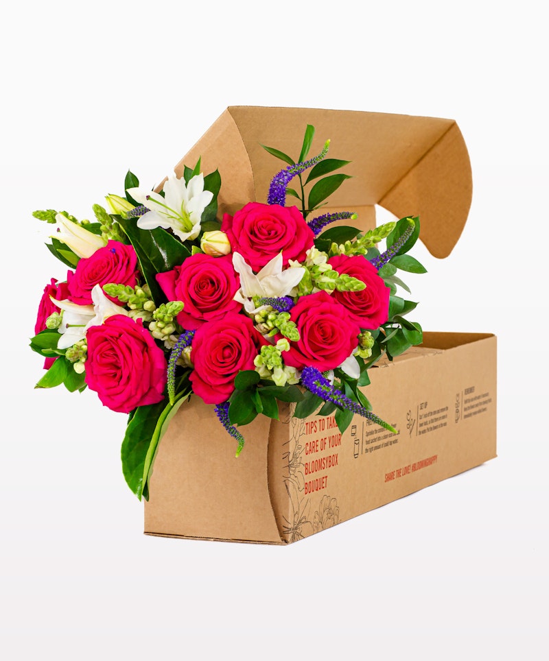 Vibrant bouquet of pink roses and white lilies with greenery packaged in a brown cardboard flower box, ready for delivery or gifting.