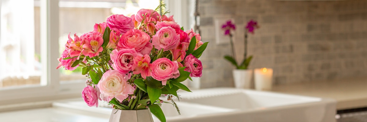 A vibrant bouquet of pink roses and greenery displayed in a stylish kitchen.