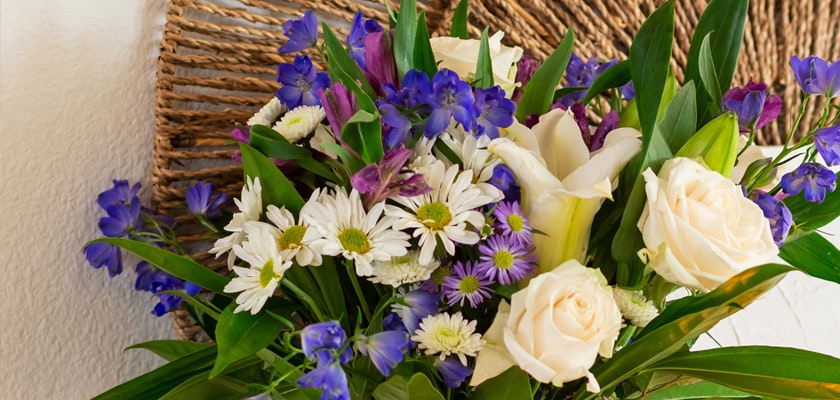 Fresh floral arrangement featuring white roses, daisies, and vibrant purple blooms.