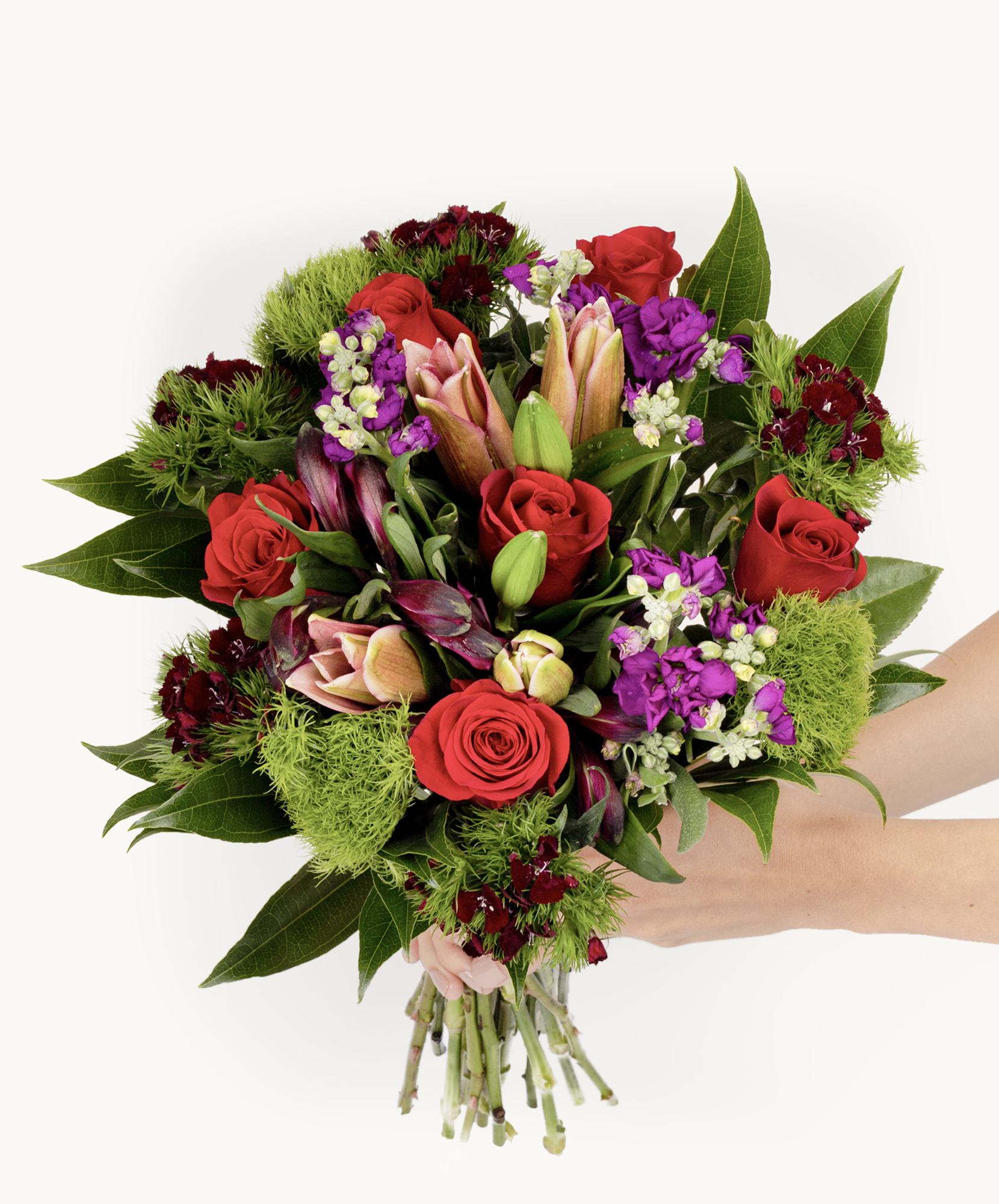 Vibrant mixed bouquet featuring red roses, lilies, and purple flowers, elegantly held by a hand.