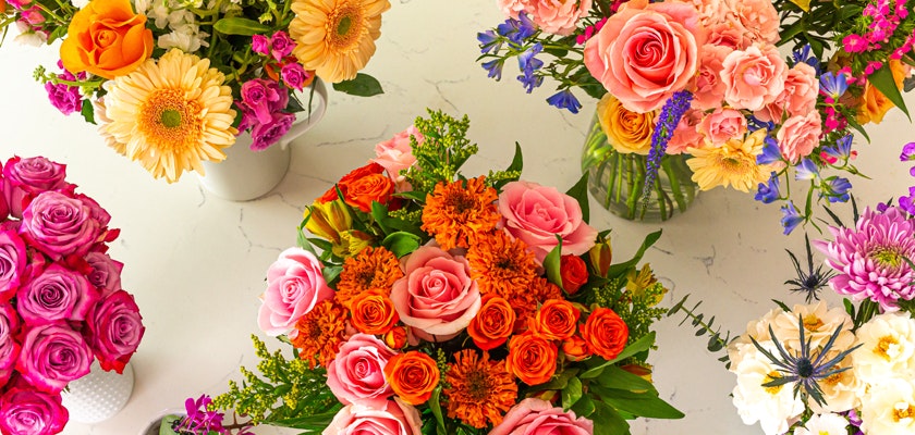 Assorted colorful flower bouquets with roses, gerberas, and lilies on a white surface, creating a vibrant display of fresh floral arrangements.