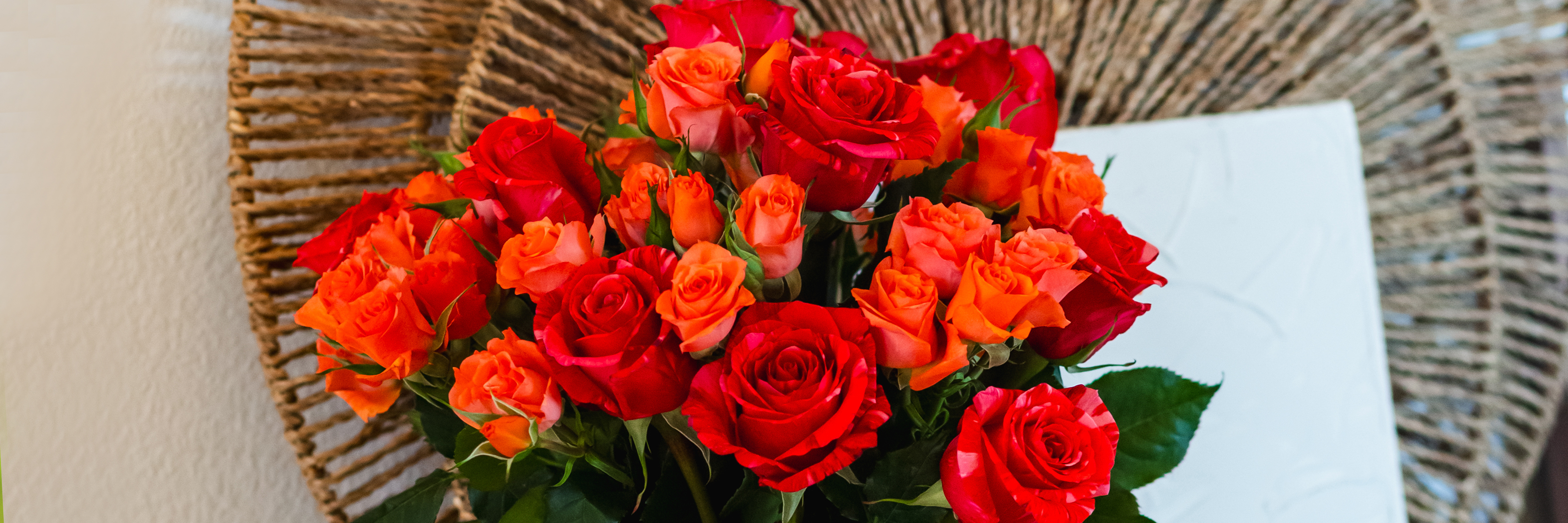 Vibrant bouquet of red and orange roses artistically arranged with lush greenery.