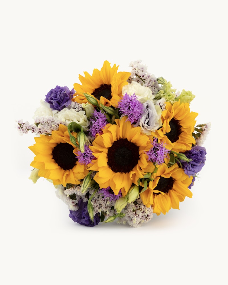 Beautiful bouquet of bright sunflowers, purple flowers, and mixed greenery arranged in a lush cluster, isolated on a white background.