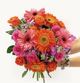 Bright and cheerful floral bouquet featuring orange gerbera daisies, pink roses, and vibrant blooms.