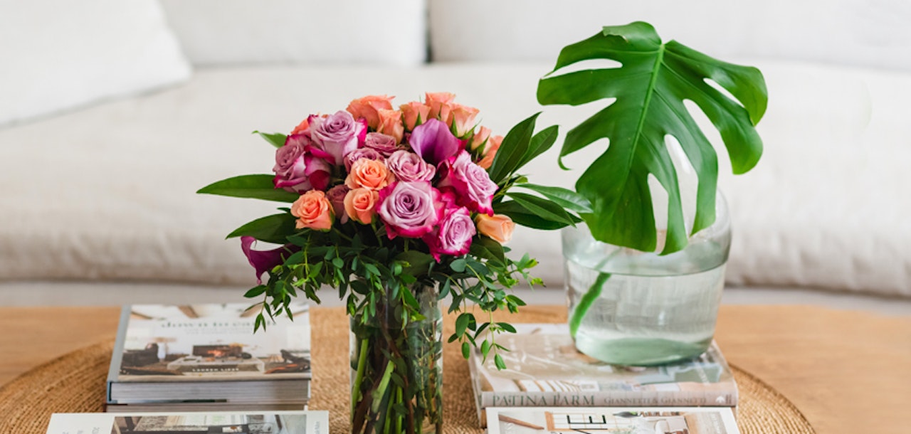 A vibrant floral arrangement featuring pink and peach roses, complemented by lush greenery.
