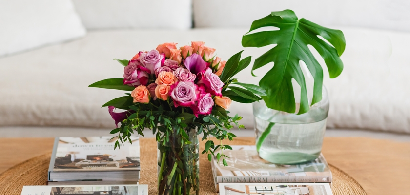 A vibrant floral arrangement featuring pink and peach roses, complemented by lush greenery.