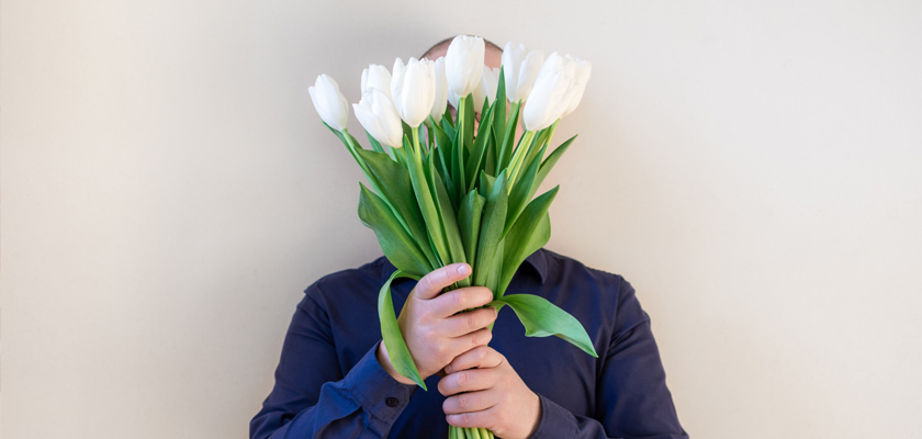 A person holding a bouquet of white tulips in front of their face, adding elegance to any occasion.
