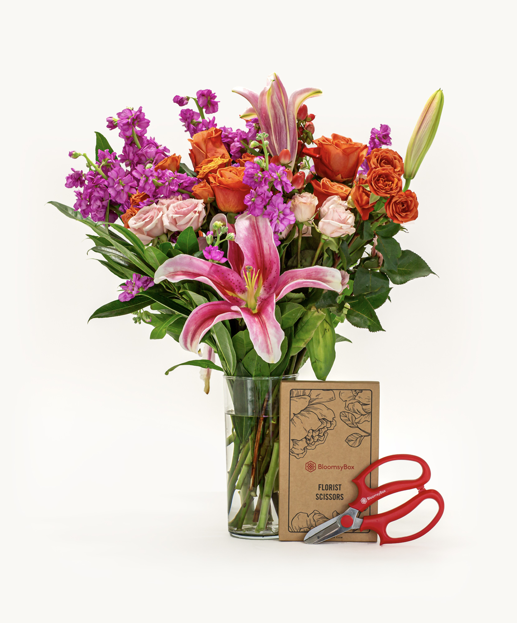 Vibrant floral arrangement featuring lilies, roses, and greenery in a decorative vase.