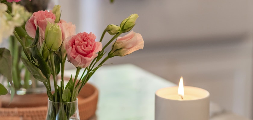 A delicate arrangement of pink flowers beside a softly glowing candle, creating a serene ambiance.