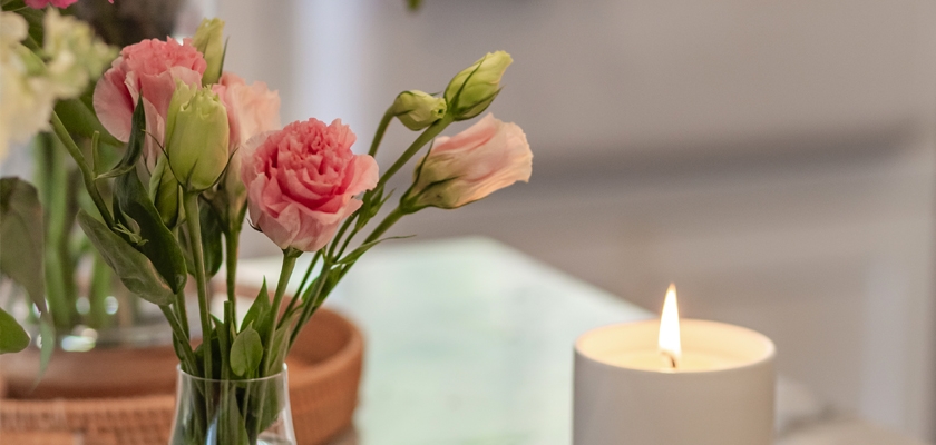 A delicate arrangement of pink flowers beside a softly glowing candle, creating a serene ambiance.