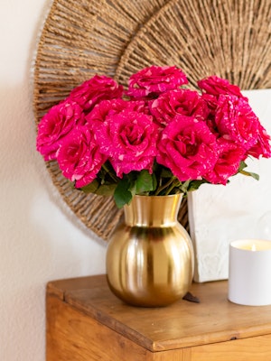 Vibrant pink roses in a chic gold vase, adding elegance to any room's decor.