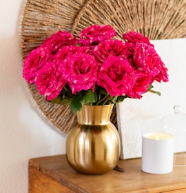 Vibrant pink roses in a chic gold vase, adding elegance to any room's decor.