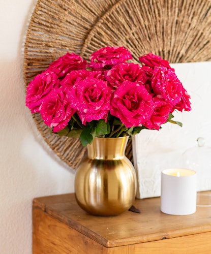 Vibrant pink roses in a chic gold vase, adding elegance to any room's decor.