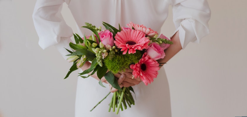 A vibrant bouquet featuring pink gerbera daisies, roses, and lush greens, perfect for celebrations.