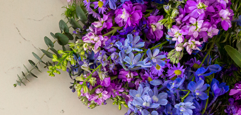 Vibrant floral arrangement featuring an array of purple and blue blooms with lush greenery.