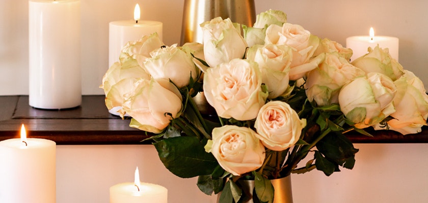 Elegant bouquet of soft white roses surrounded by glowing candles, creating a serene atmosphere.