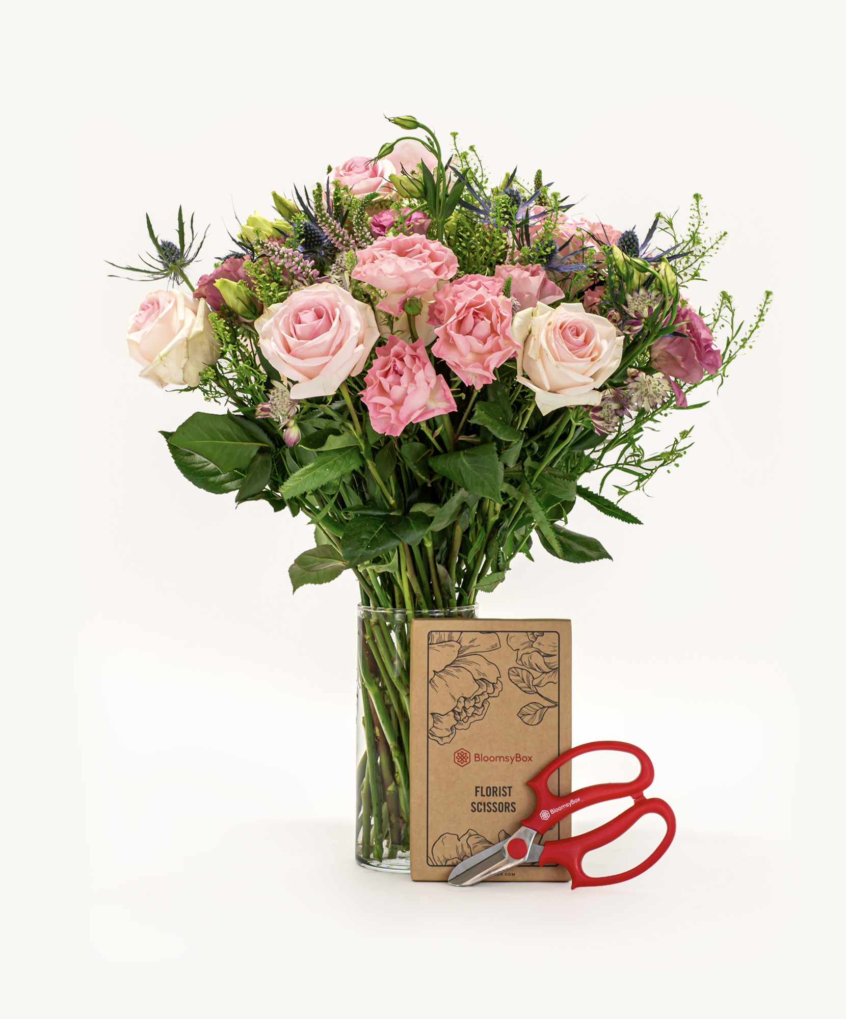 A lovely floral bouquet featuring pink and cream roses, complemented by greenery and scissors.