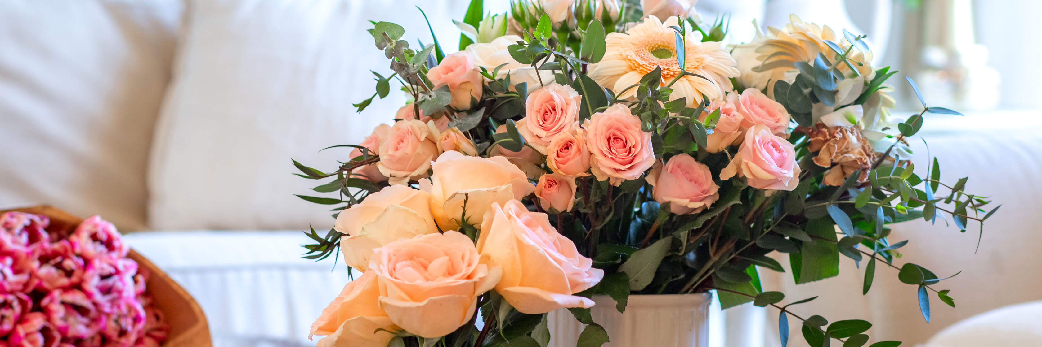 Delicate arrangement of pink roses and white florals with lush greenery in a stylish vase.