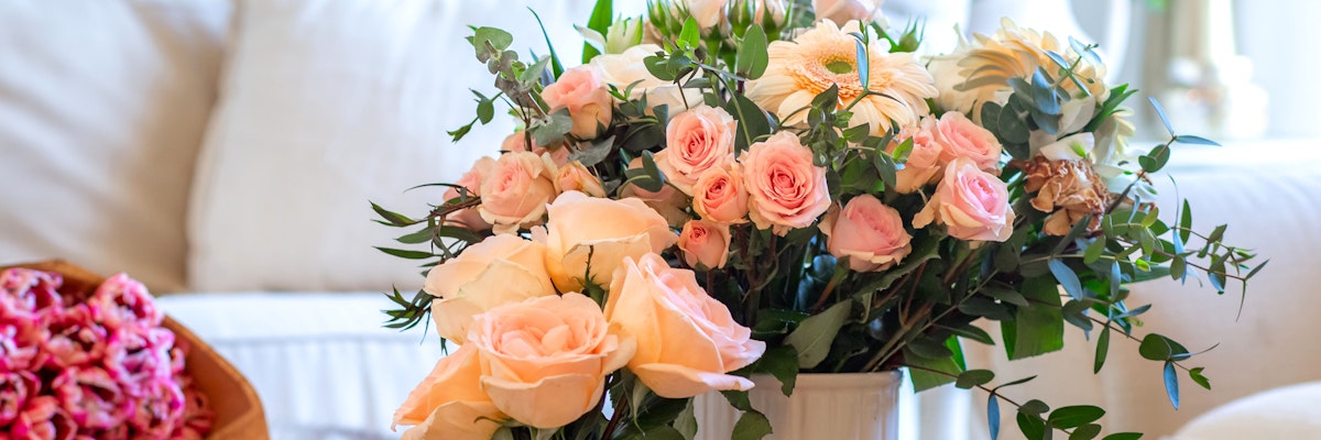 Delicate arrangement of pink roses and white florals with lush greenery in a stylish vase.