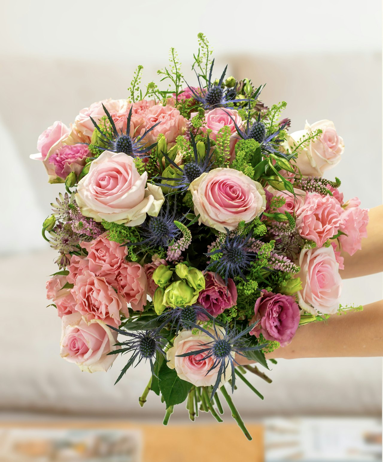 Beautifully arranged bouquet featuring soft pink roses, vibrant green accents, and purple blooms.