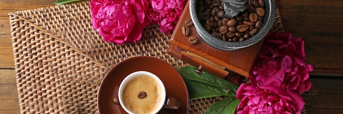 A cozy coffee scene featuring a cup of espresso, peonies, and coffee beans. Ideal for coffee lovers.