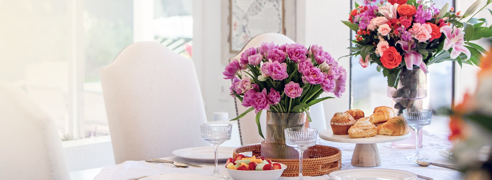 Elegant dining table set with vibrant floral arrangements and delicious pastries.