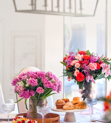 Elegant floral arrangements featuring pink and red blooms on a beautifully set table.