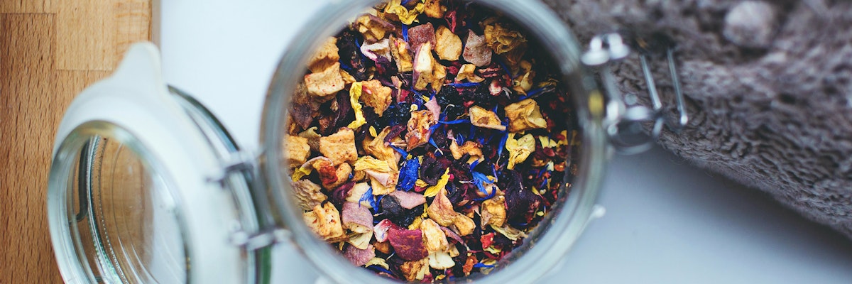 A glass jar filled with colorful dried flowers and herbs, perfect for tea blends and aromatherapy.