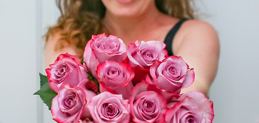 A beautiful bouquet of pink and lavender roses held by a smiling woman, ideal for gifting.