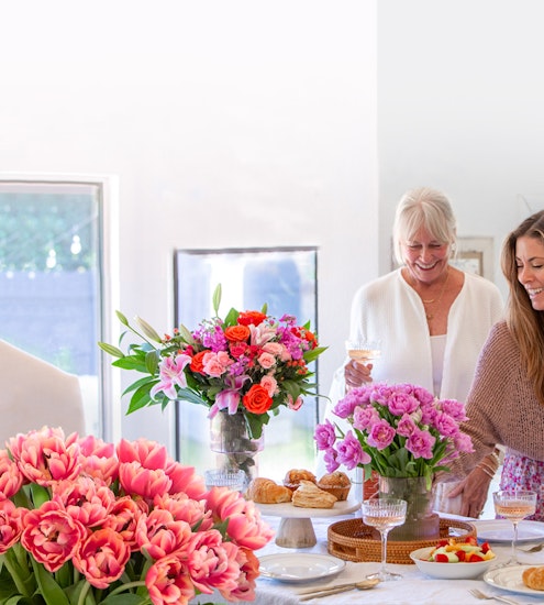 Brightly decorated dining table with vibrant floral arrangements and joyful guests enjoying brunch.