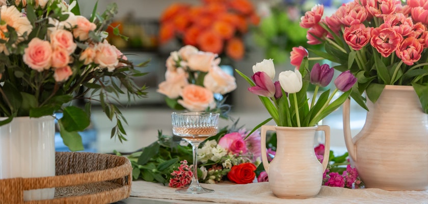 Elegant floral display featuring pink tulips and soft peach roses in stylish vases.