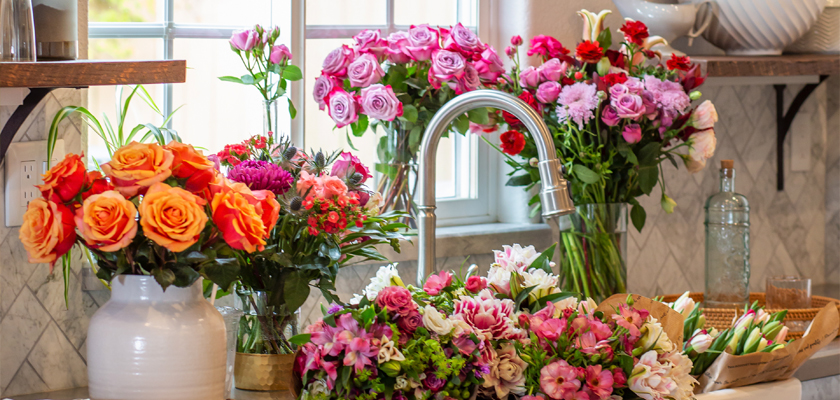 Vibrant floral arrangements featuring roses, lilies, and daisies in a sunny kitchen setting.