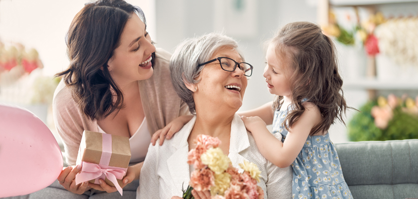 A joyful family moment with a grandmother, daughter, and granddaughter celebrating together at home.