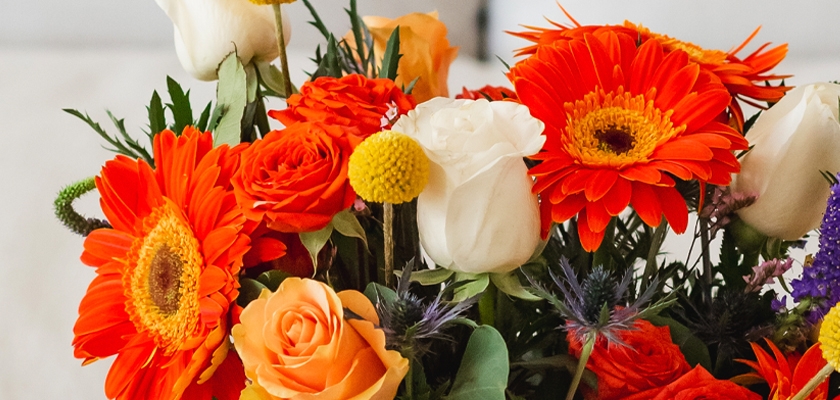 Vibrant floral arrangement featuring orange gerberas, white roses, and yellow accents.