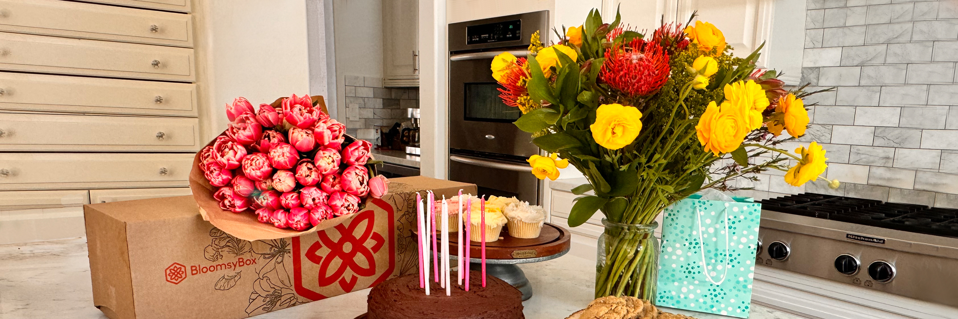 Vibrant birthday celebration with colorful flowers, cake, and treats on a kitchen table.