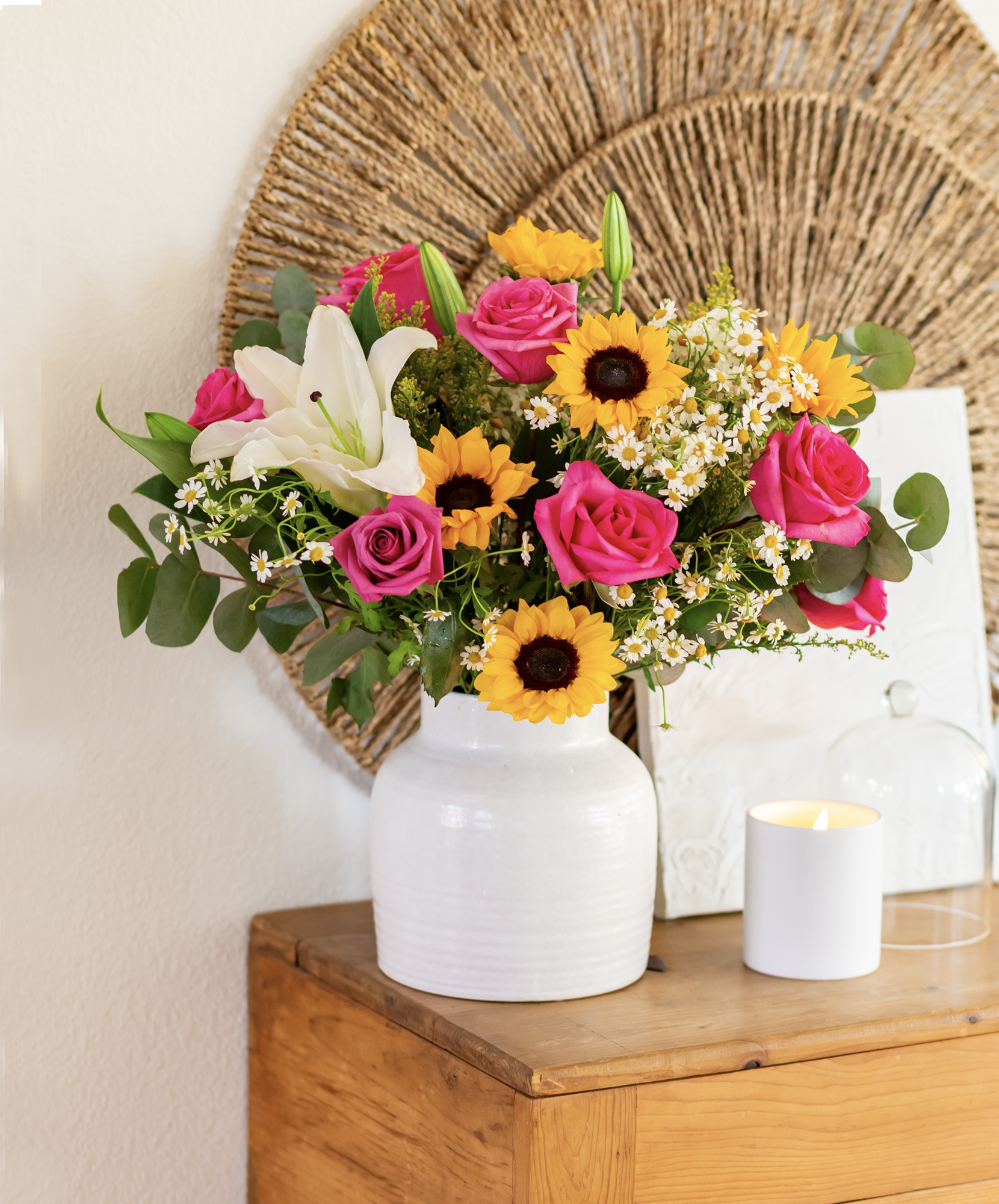 Vibrant floral arrangement featuring pink roses, sunflowers, and lilies in a stylish white vase.