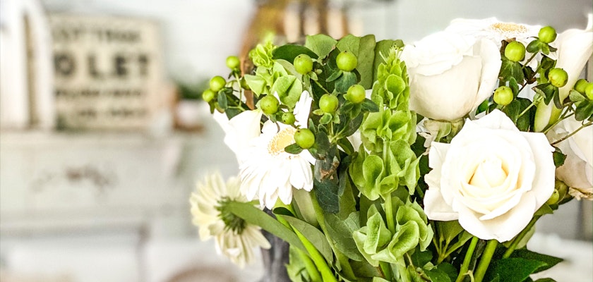 Elegant white roses and green accents create a sophisticated floral arrangement for any occasion.