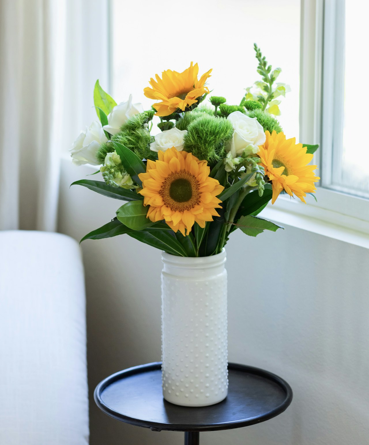 Bright sunflowers and white roses in a textured vase, enhancing any room decor.