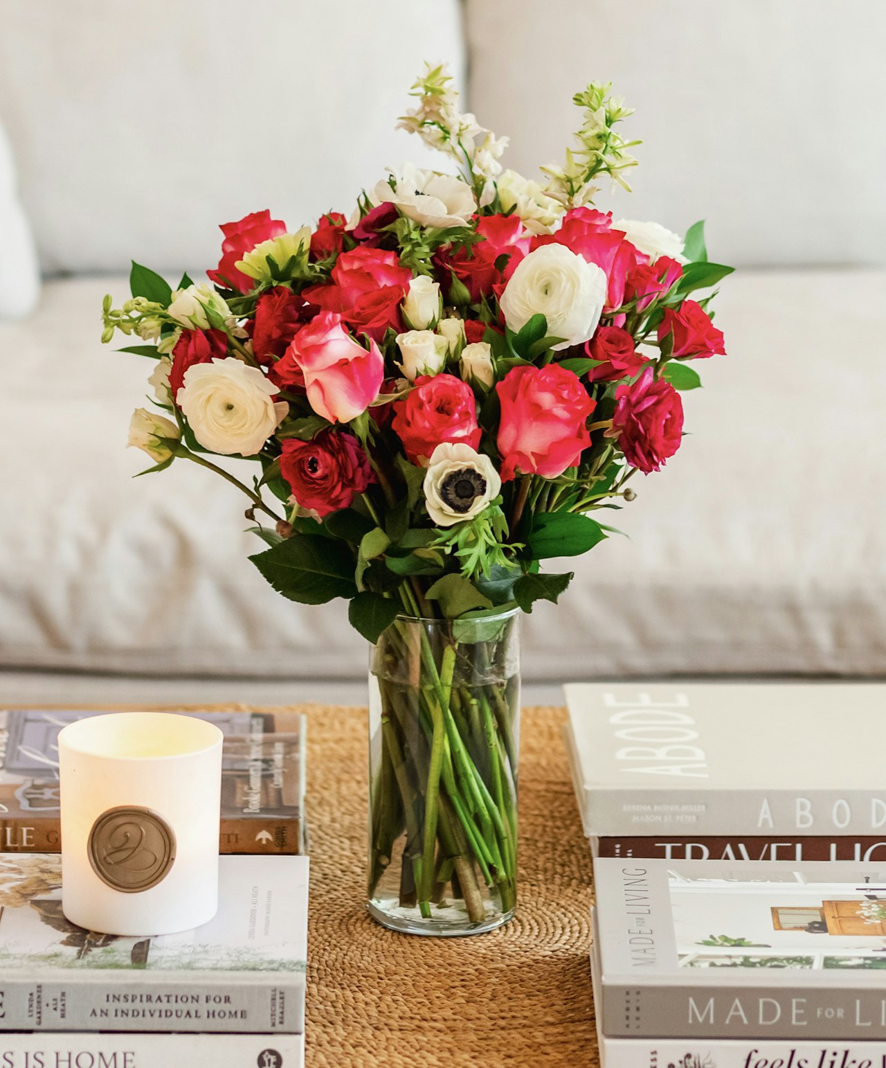 Vibrant mixed bouquet of pink, white, and red flowers in a glass vase on a coffee table.