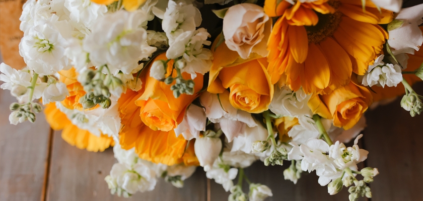 Bright floral bouquet featuring sunflowers, white roses, and delicate blooms arranged beautifully.