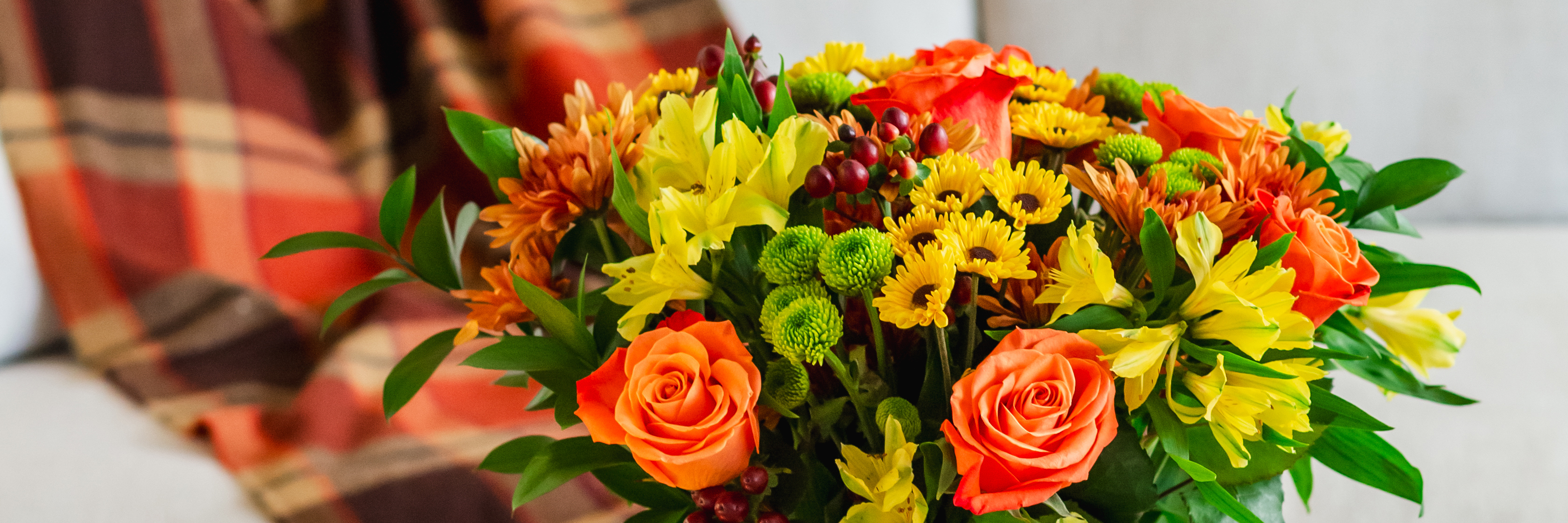 Vibrant bouquet of orange roses, yellow daisies, and greenery, perfect for autumn decorating.