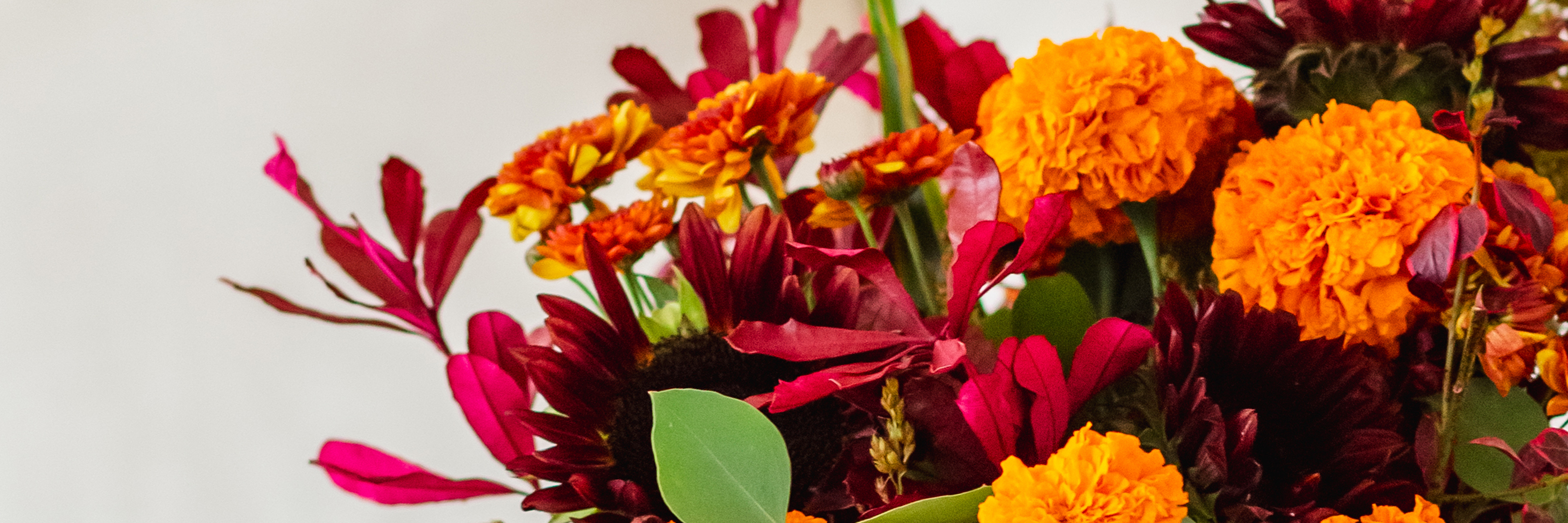 Vibrant floral arrangement featuring marigolds, zinnias, and rich foliage in warm autumn hues.