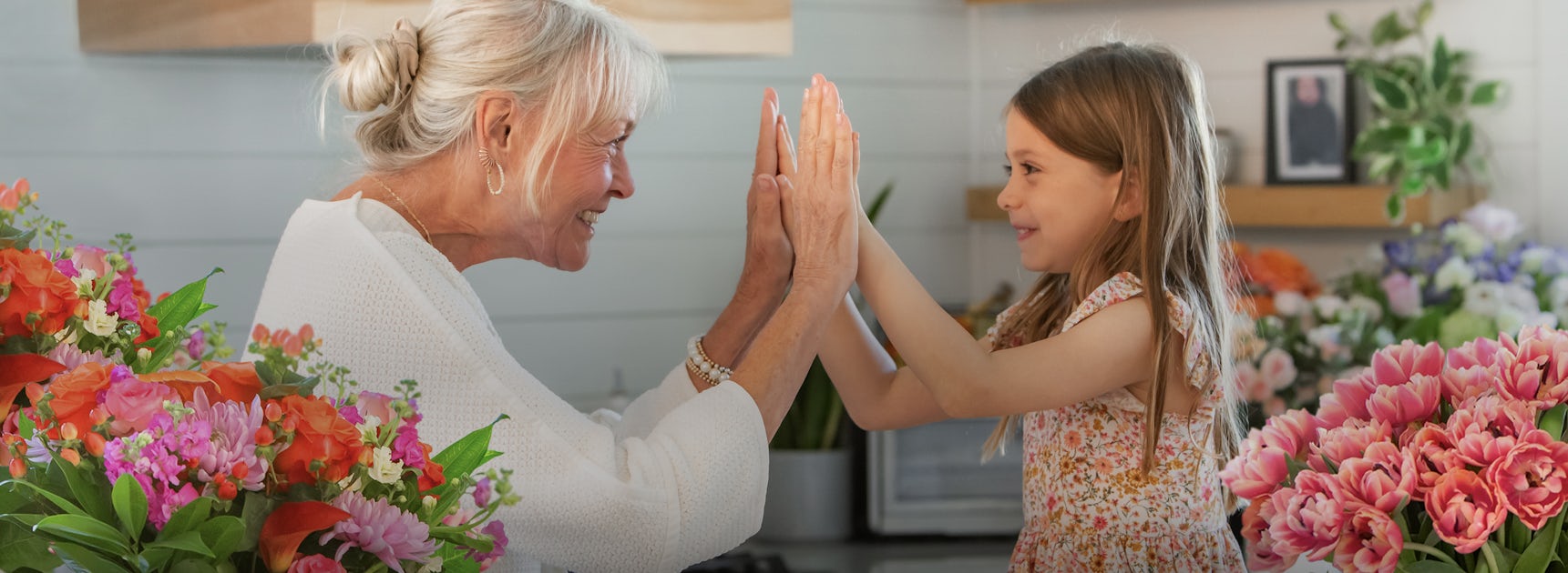 A joyful moment between a grandmother and granddaughter, surrounded by vibrant floral arrangements.