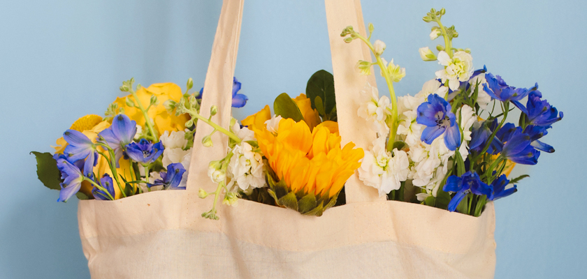 Brightly colored flowers in a tote bag, showcasing a vibrant spring arrangement.