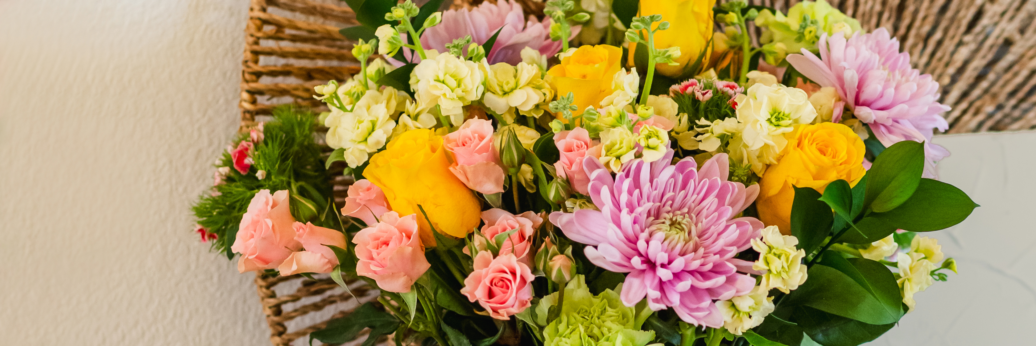Vibrant floral arrangement featuring yellow roses, pink and white blooms, and lush greenery.