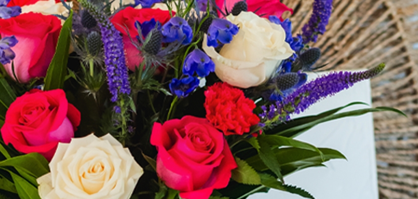 Vibrant floral arrangement featuring red, white roses and purple blooms, perfect for celebrations.