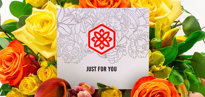 Vibrant flower arrangement featuring yellow, orange, and red blooms with a cheerful card.