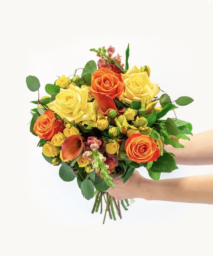 Vibrant bouquet of yellow and orange roses with lush greenery, perfect for any celebration.