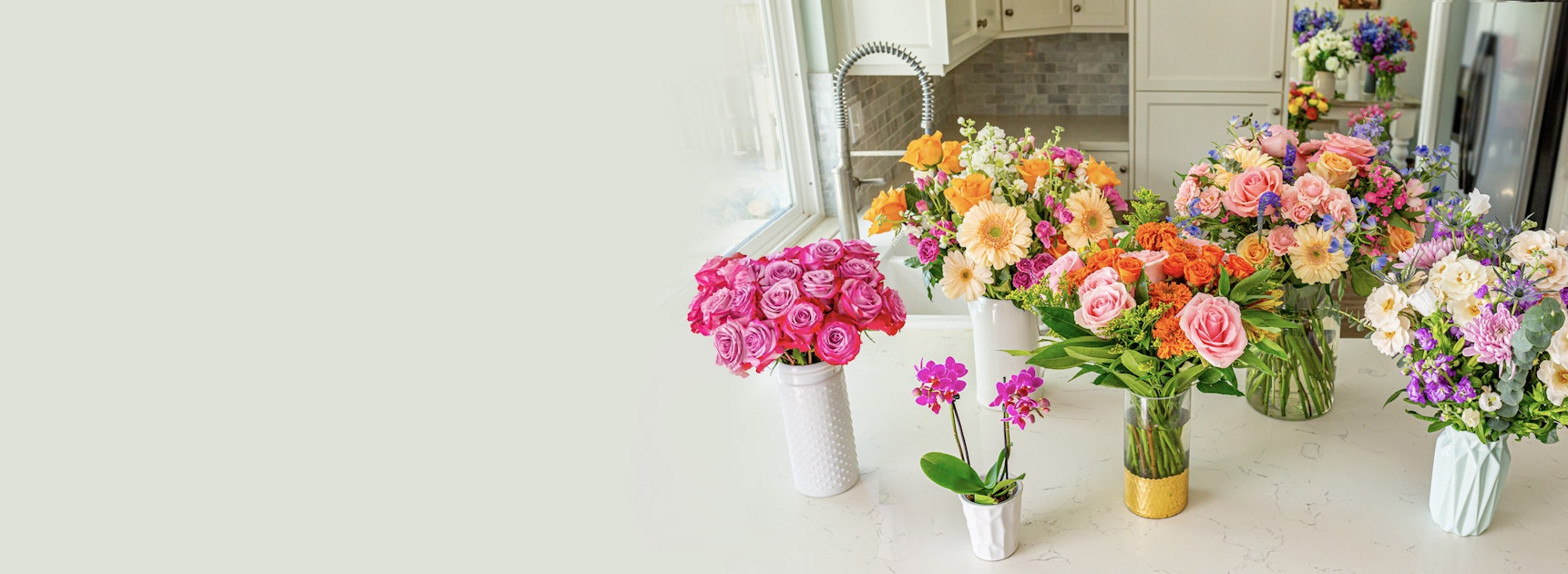 Vibrant flower arrangements on a countertop, featuring roses, orchids, and mixed blooms.